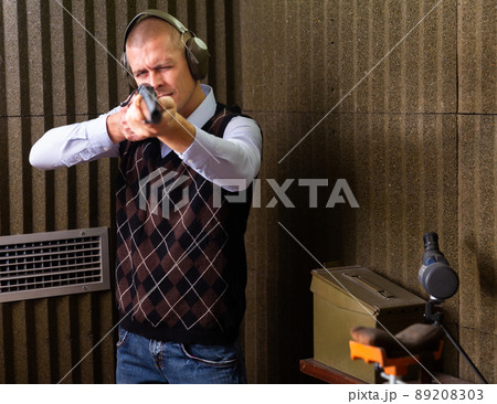 Concentrated man practicing shotgun shooting at firing range Concentrated man practicing shotgun shooting at firing range 89208303