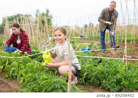Mother and daughter watering plants at garden closeup 89208402