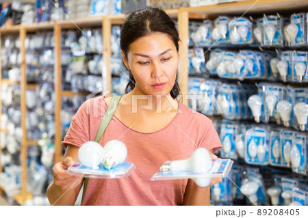 Woman choices energy saving lamp at hardware store 89208405