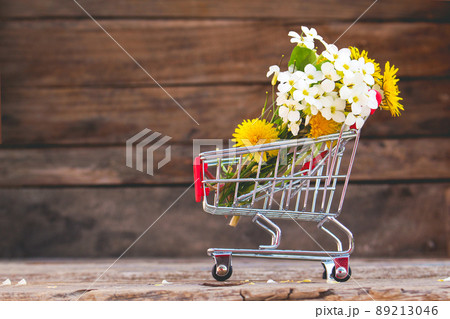 Shopping cart with flowers on the wooden background. 89213046