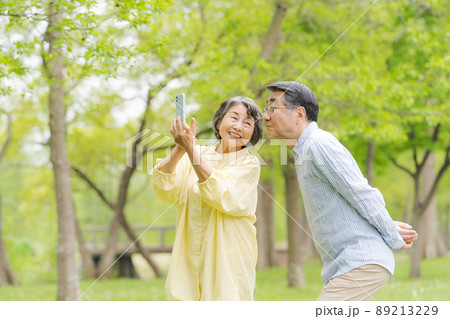 スマホを持つシニア男女　公園 89213229