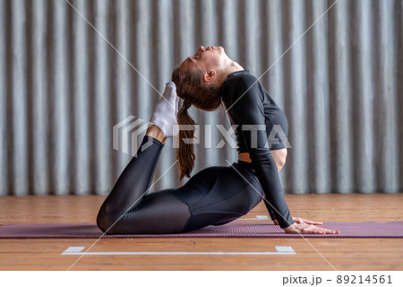 Woman working out arching her back and reaching her toes for her head 89214561