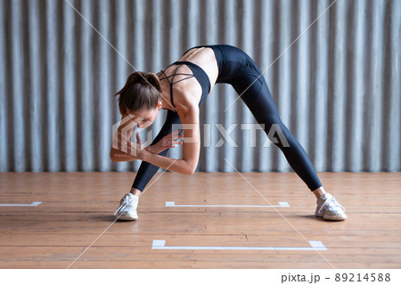 Woman exercising standing forward bend stretches of legs and lower back. 89214588