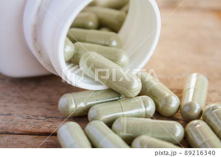 Herbal capsules spilling out of a bottle 89216340