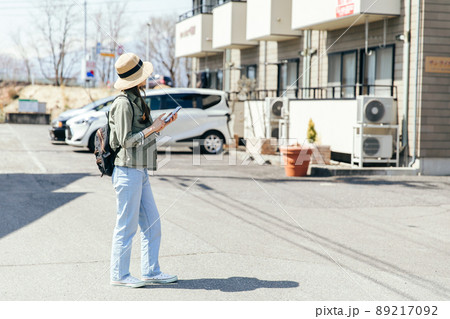 携帯電話を片手に家を探す人　Property search	 89217092