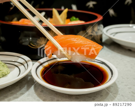 Salmon sushi in chopsticks dipping with soy sauce 89217290