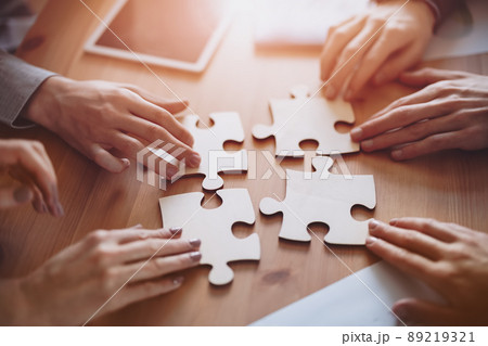 Buisnesswomen and buisnessmen working together while putting together puzzles. Buisnesswomen and buisnessmen working together while putting together puzzles. 89219321