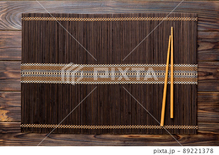 Two chopsticks and bamboo mat on wooden background. Top view, copy space Two chopsticks and bamboo mat on wooden background. Top view, copy space 89221378