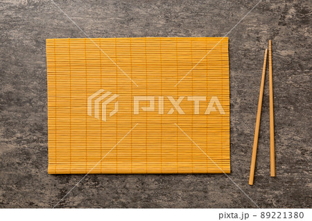 Two chopsticks and bamboo mat on cement background. Top view, copy space Two chopsticks and bamboo mat on cement background. Top view, copy space 89221380