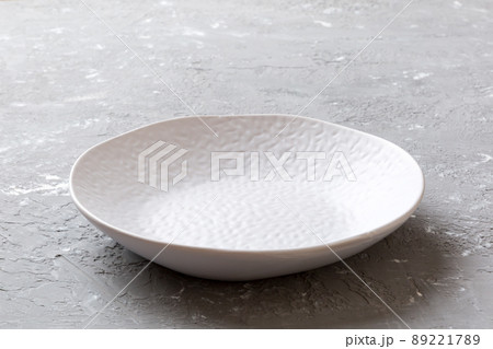 Perspective view of empty light plate on cement background. Empty space for your design Perspective view of empty light plate on cement background. Empty space for your design 89221789