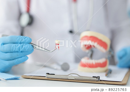 Dentist is holding tooth and dental tool closeup Dentist is holding tooth and dental tool closeup 89225763