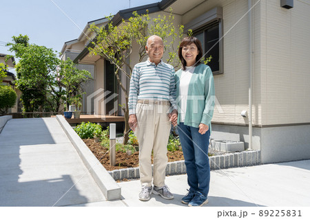 自宅の庭の前で2人で並んで立つシニア夫婦 89225831