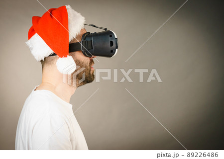 Man in virtual reality goggles and santa hat Man in virtual reality goggles and santa hat 89226486