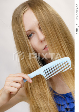 Woman combing long healthy blonde hair Woman combing long healthy blonde hair 89226522