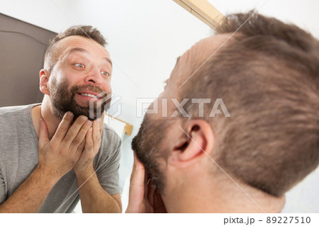 Man looking at beard in mirror Man looking at beard in mirror 89227510