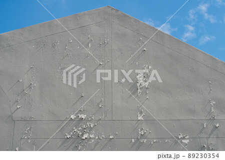 Close up of peeling paint on a grey concrete wall. Grungy cracked grey wall paint peeling off Close up of peeling paint on a grey concrete wall. Grungy cracked grey wall paint peeling off 89230354