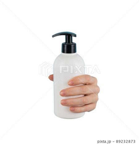A woman's hand sticks out of a hole in a white background and holds a skin lotion pump. 89232873