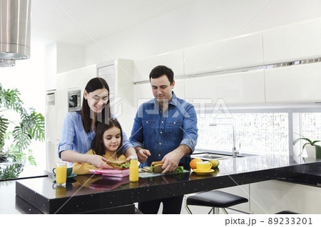 Happy smiling young family enjoying healthy breakfast together with there little daughter Happy smiling young family enjoying healthy breakfast together with there little daughter 89233201