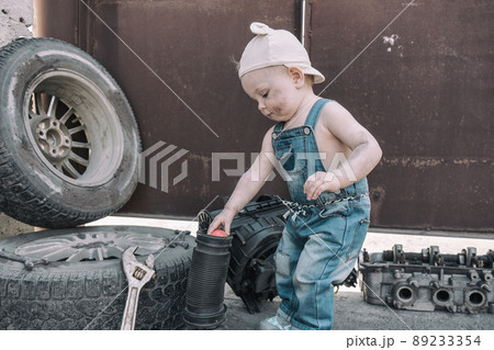 one year old baby playing mechanic among auto parts 89233354
