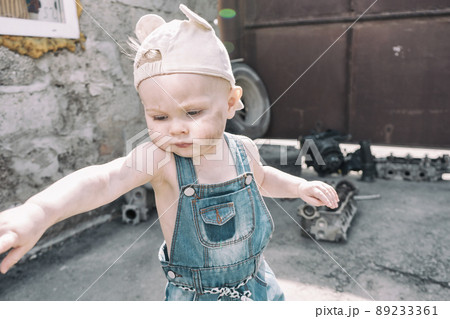 one year old baby in overalls with dirty face stands and waving his arms one year old baby in overalls with dirty face stands and waving his arms 89233361