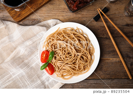 Tasty buckwheat noodles with chopsticks on wooden table, flat lay Tasty buckwheat noodles with chopsticks on wooden table, flat lay 89235504