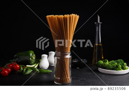 Uncooked buckwheat noodles and fresh ingredients on black table Uncooked buckwheat noodles and fresh ingredients on black table 89235506