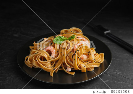 Tasty buckwheat noodles with shrimps on black table Tasty buckwheat noodles with shrimps on black table 89235508