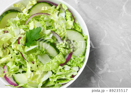 Tasty salad with cabbage and cucumbers on light grey marble table, top view 89235517