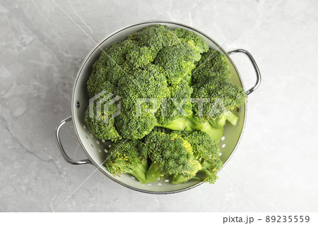 Fresh green broccoli in colander on grey marble table, top view 89235559
