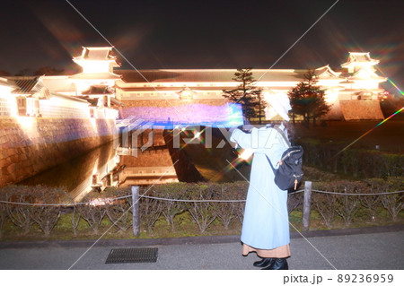 金沢のライトアップの城を観光する一人旅の女性の残像の写真素材