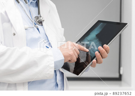 Unrecognizable Doctor is checking x-ray image at computer tablet, close up. Doctor at work in a 89237652