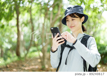 森林でスマートフォンを使う女性 89240617