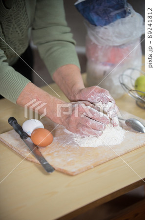 An old lady making little pies. Knead the dough on the desk An old lady making little pies. Knead the dough on the desk 89241812