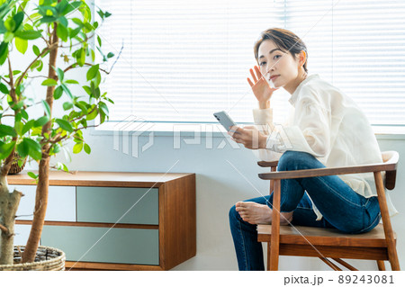明るい窓際でスマホを使うミドルの女性 89243081