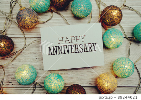 Happy Anniversary text on paper card with LED Cotton ball Decoration on wooden background Happy Anniversary text on paper card with LED Cotton ball Decoration on wooden background 89244021