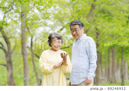スマホを持つシニア男女　公園 89246932