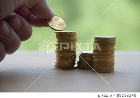 Hand stacking gold coins on wooden background. Business concept 89253249