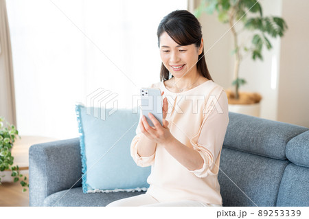 部屋でスマホを操作するミドル女性 部屋でスマホを操作するミドル女性 89253339