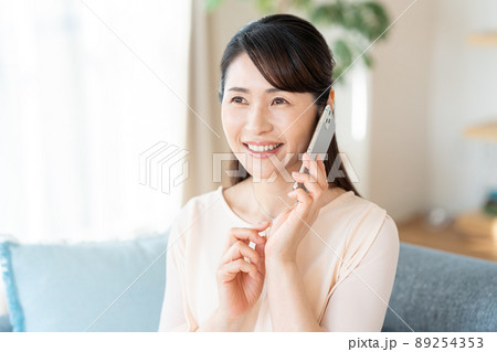 部屋でスマホを操作するミドル女性 89254353