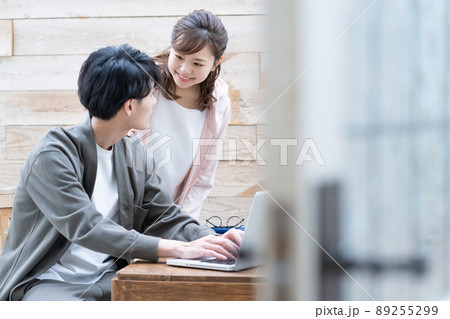 リモートワークする若い男性とそばで見守る奥さん リモートワークする若い男性とそばで見守る奥さん 89255299