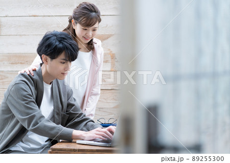 リモートワークする若い男性とそばで見守る奥さん 89255300