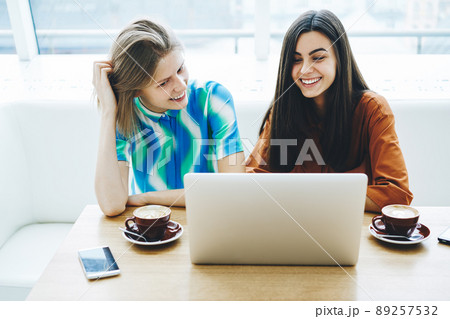 Smiling female students with laptop studying together 89257532