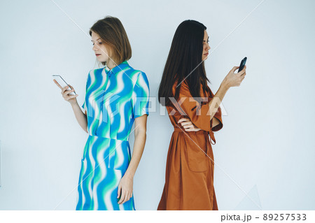 Women standing near wall with phone in hand 89257533
