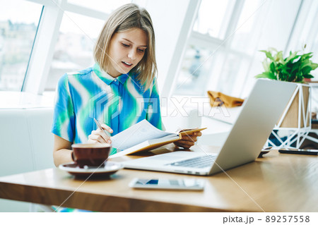 Student reading book and using laptop in cafe 89257558