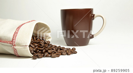 Coffee beans spilled out of the bag on a white background. Brown mug. Isolate. 89259905
