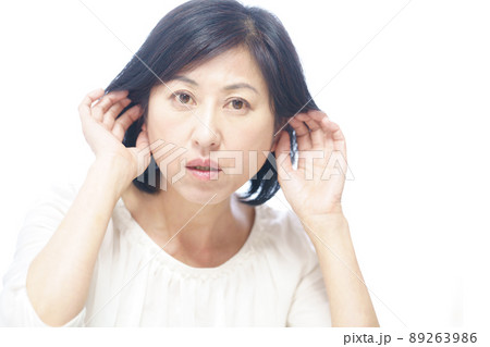 不快そうに耳に手をやる中年女性 不快そうに耳に手をやる中年女性 89263986