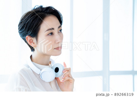 ヘッドホンを首にかけるミドルの女性 89266319