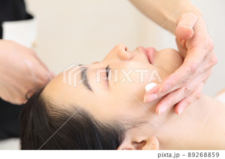 エステシャンとクリームを塗る頬近くの手と若い女性 89268859