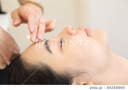 エステシャンとクリームを塗るおでこ近くの手と若い女性 エステシャンとクリームを塗るおでこ近くの手と若い女性 89268860