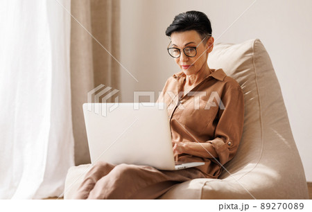 Middle aged woman using laptop at home 89270089